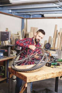 man pulling apart wheel rim and tire of a bicycle wheel at a wooden work&hellip;
